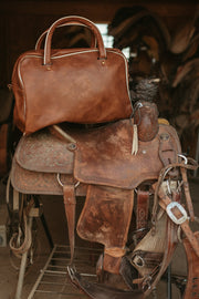 Horse Girl vegan leather bag resting on a western saddle
