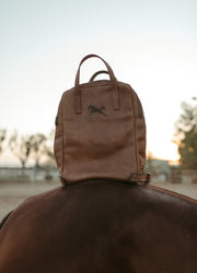 The Margaux leather backpack resting on a horse's back at sunset