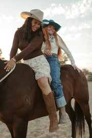 Two riders on a horse, one wearing The Tahlia tall suede boots